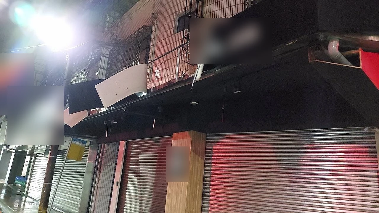 颱風後店面招牌面板被掀開懸掛的實拍，招牌維修前要先看固定點
